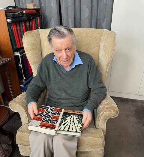 A man sitting at home with a selection of books.