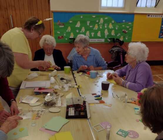 Service users sitting round a table doing a craft activity.