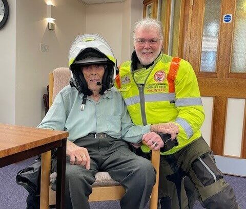 Blood Bikes Visit the club, one service user tries on the helmet and poses for the camera with the volunteer.